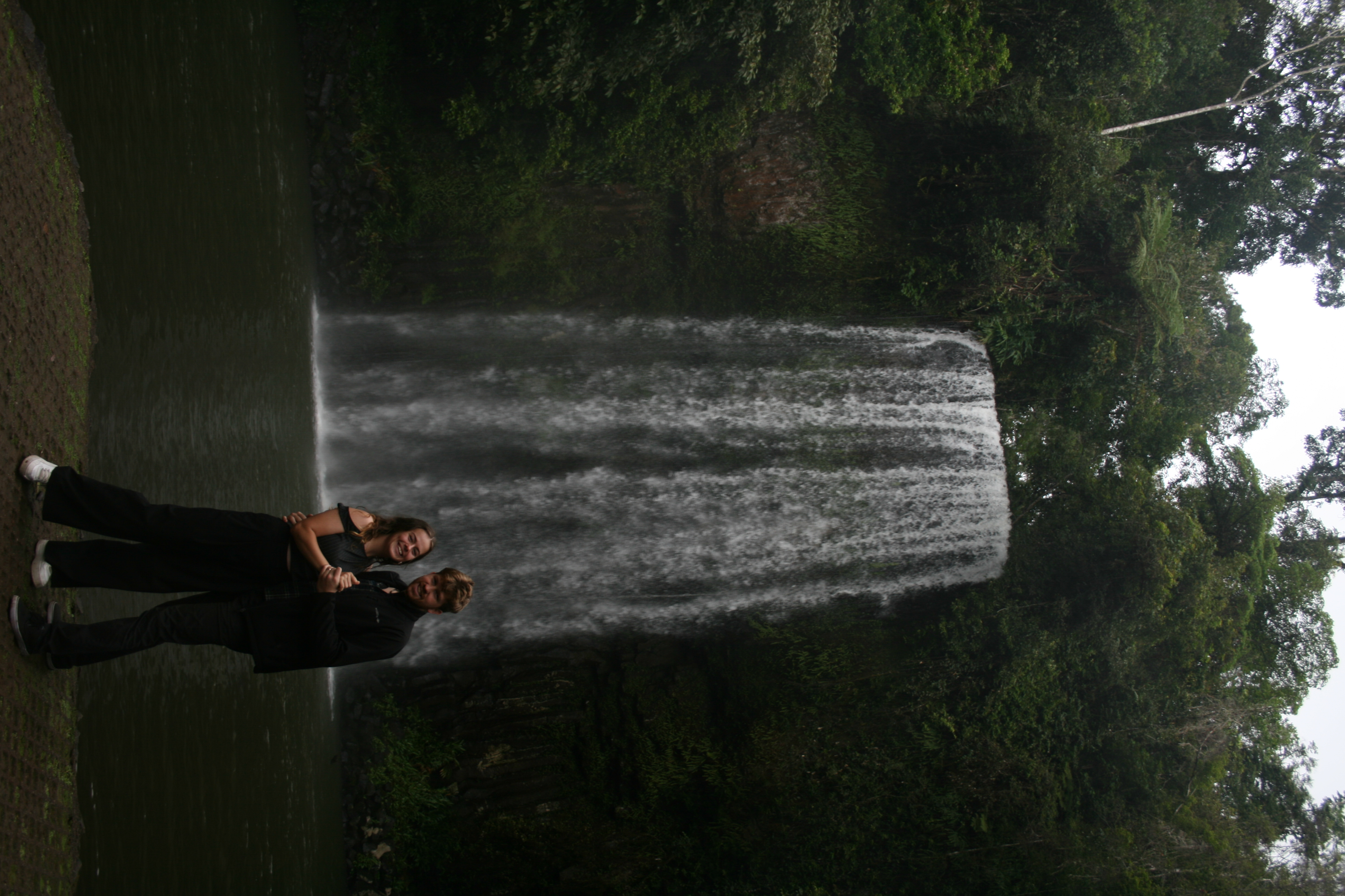 Abrie and Lydia standing together in front of a rainforest waterfall